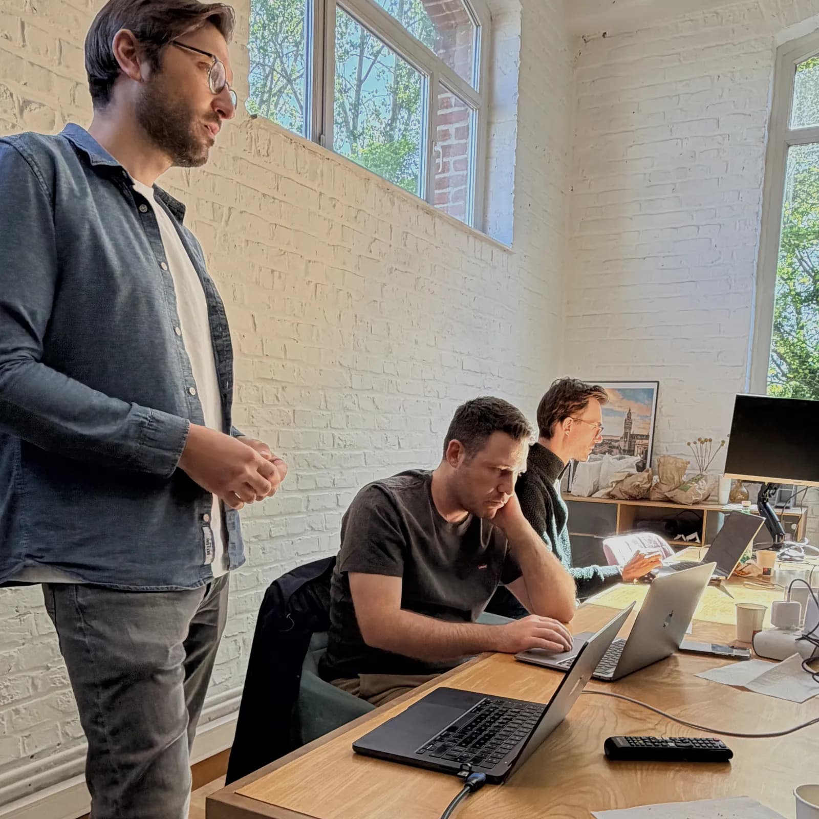 Un expert Hoko échange debout avec un développeur concentré sur son code.