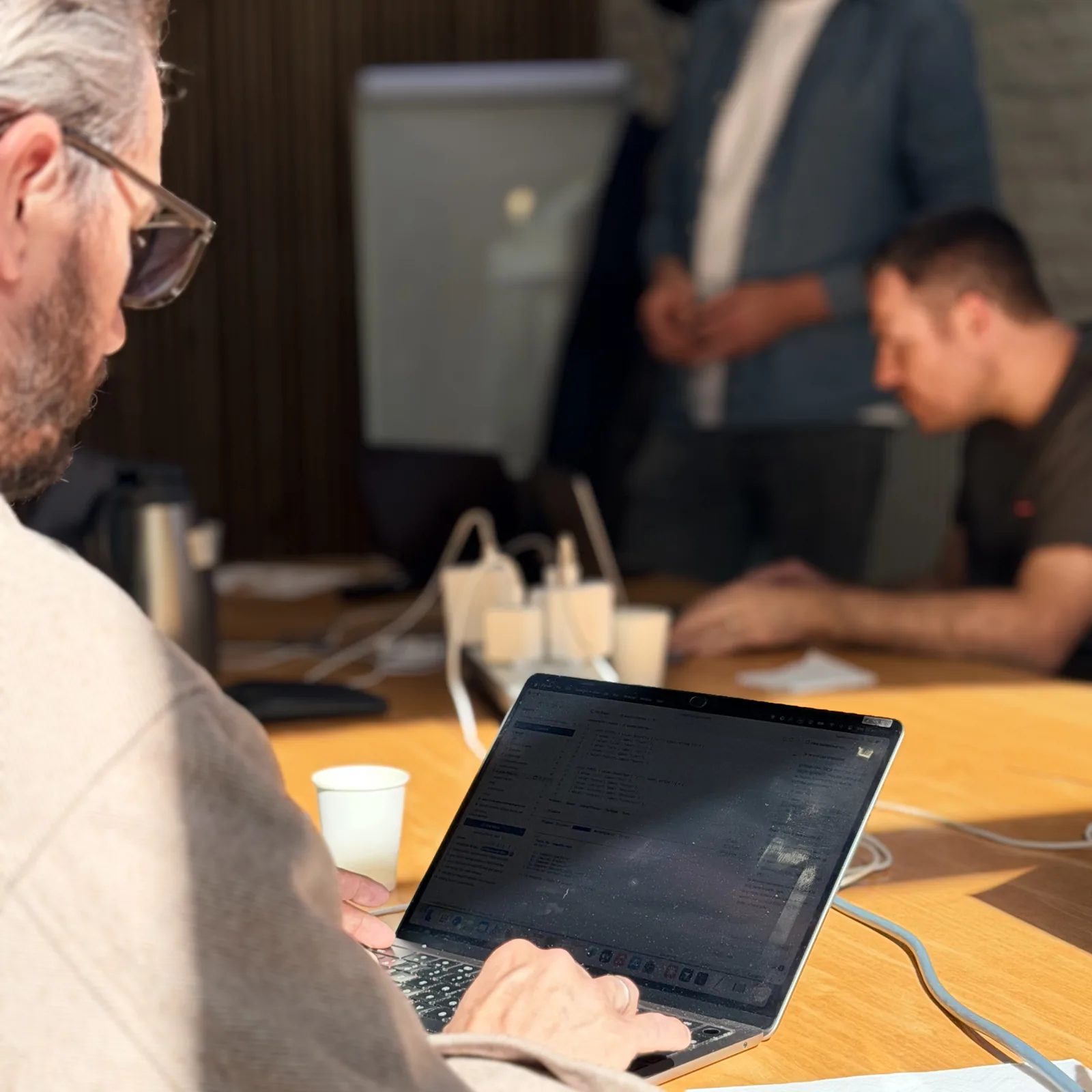 Un participant du bootcamp travaille sur son ordinateur portable, un formateur l'accompagne.