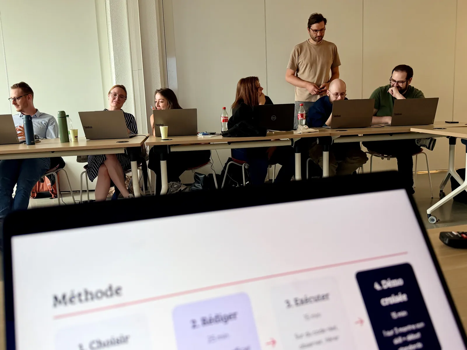 Formation Hoko : une équipe tech travaille sur ses ordinateurs portables, un formateur debout, la slide « Méthode » au premier plan.