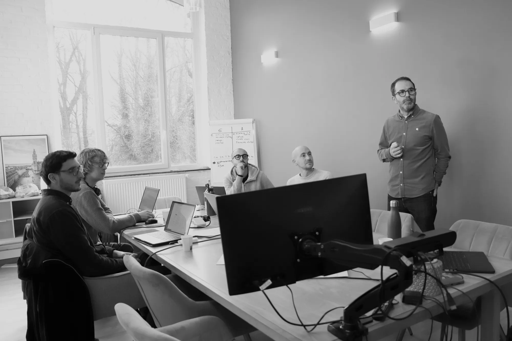 Un formateur Hoko debout anime un atelier devant une équipe, un support Claude Code projeté à l'écran.